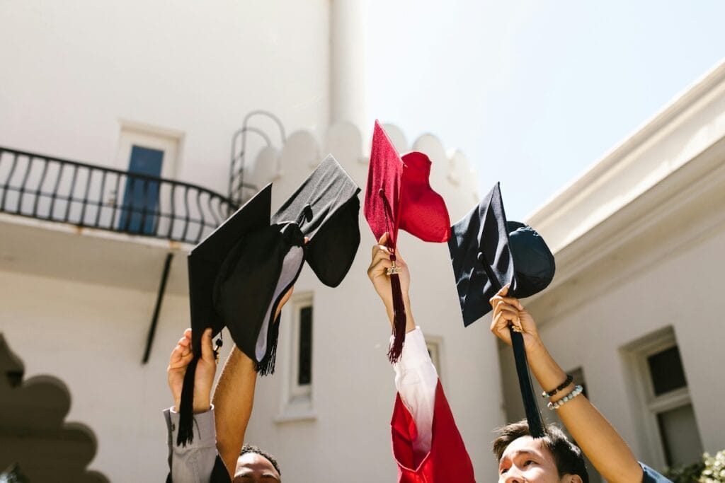Graduates holding caps celebrating outside building