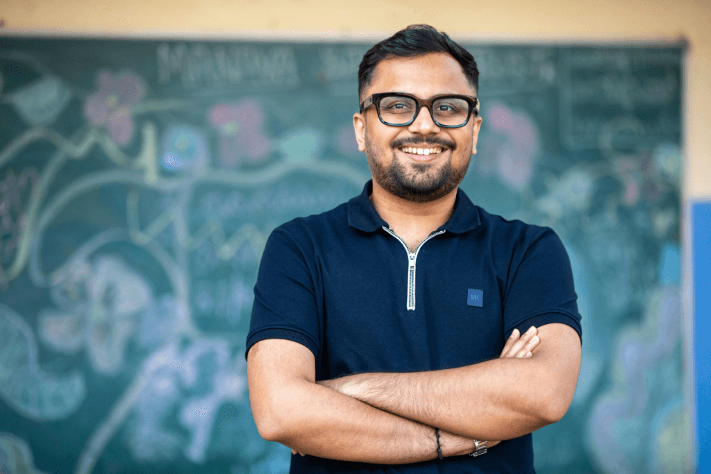 Smiling man with glasses standing before chalkboard